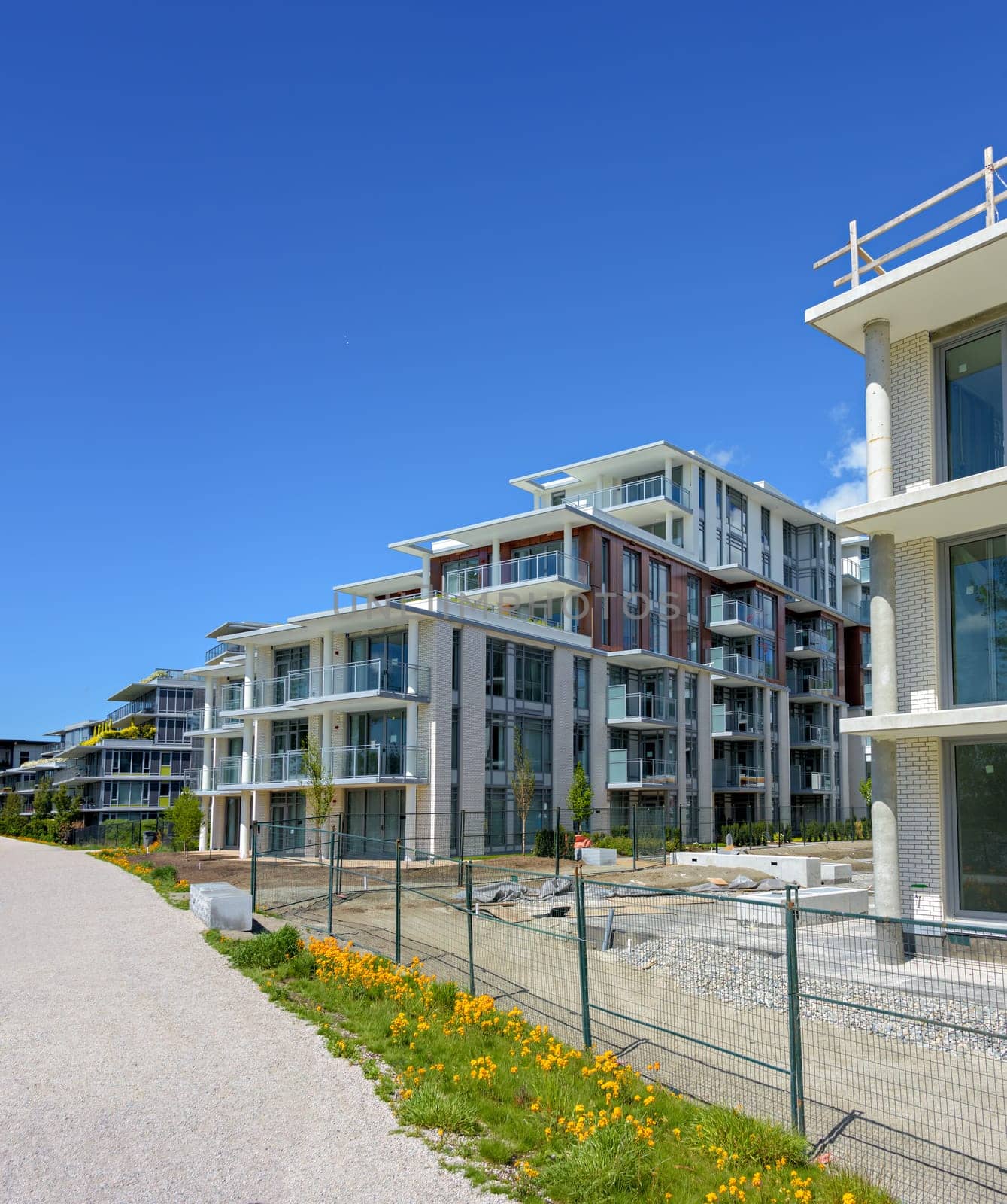 Gravel pathway along the new residential buildings on blue sky background