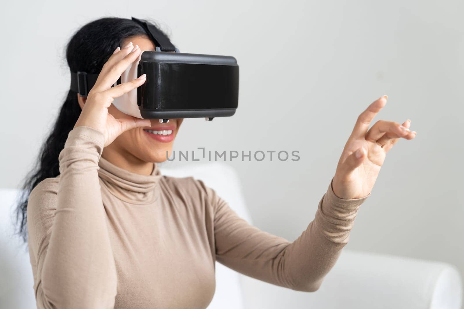 Young woman using virtual reality VR goggle at home for crucial experience by biancoblue