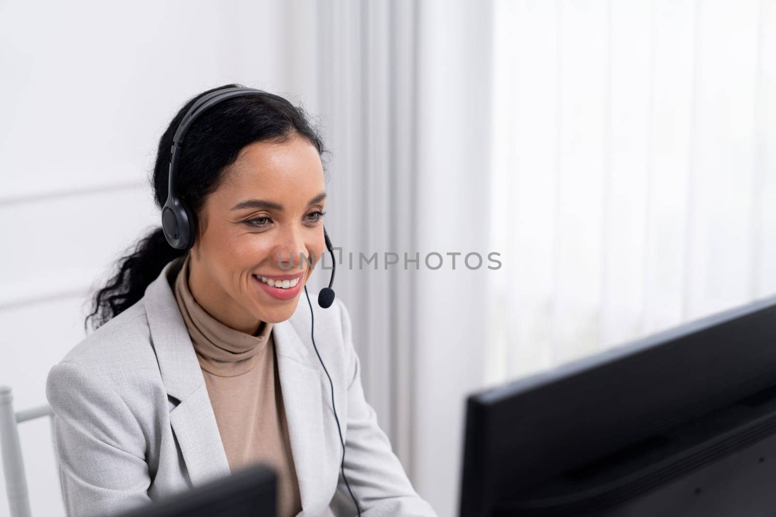 African American businesswoman wearing headset working in office to support remote crucial customer or colleague. Call center, telemarketing, customer support agent provide service on video call.