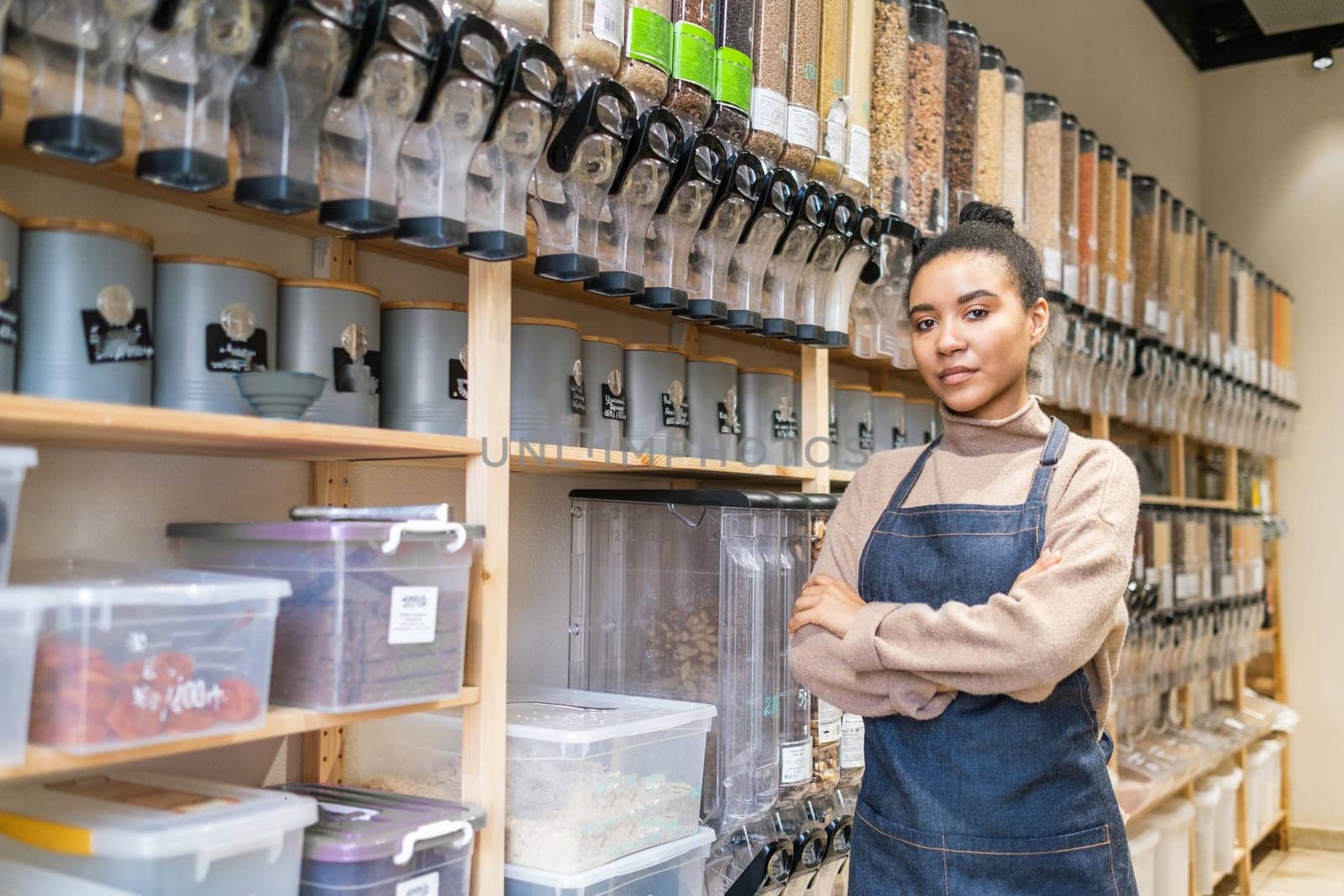 Portrait of confident African American woman owner of local zero waste grocery store wearing apron in sustainable eco grocery store by dmitryz