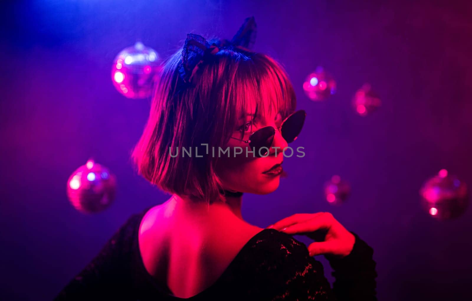 Portrait of young pretty woman in neon light. Pussy cat costume for halloween party. Sexy elegant lady with sunglasses and lace ears. High quality 4k footage