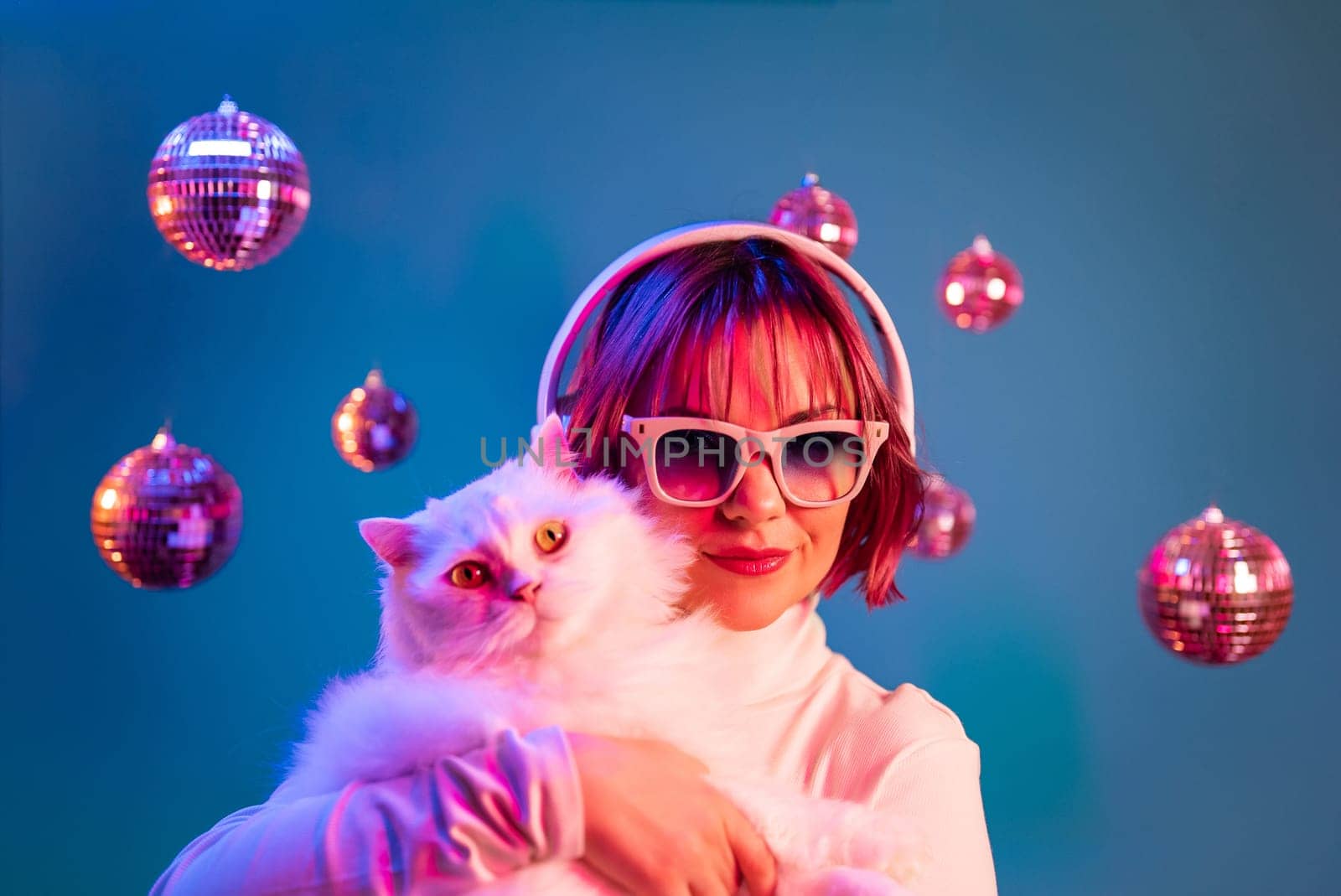 Disco woman with cat in fashion glasses listening music, dancing with headphones in colorful studio. Party, radio, headset concept.