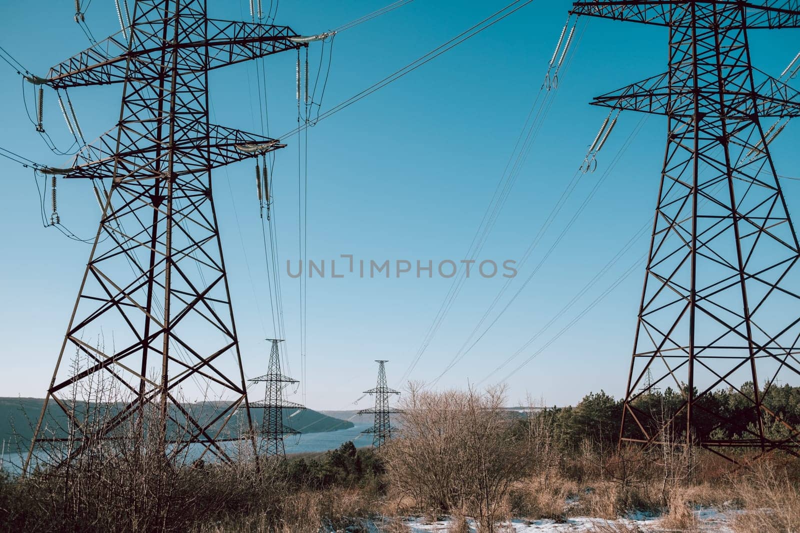 Electric voltage towers, transmission power lines, electricity pylons at sunny sky background. Renewable green energy and clean ecological environment. High quality photo