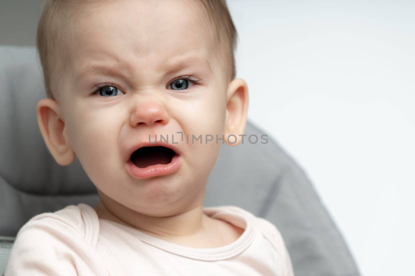 Portrait of crying 1-year old baby upset of being hungry and tired by Mariakray