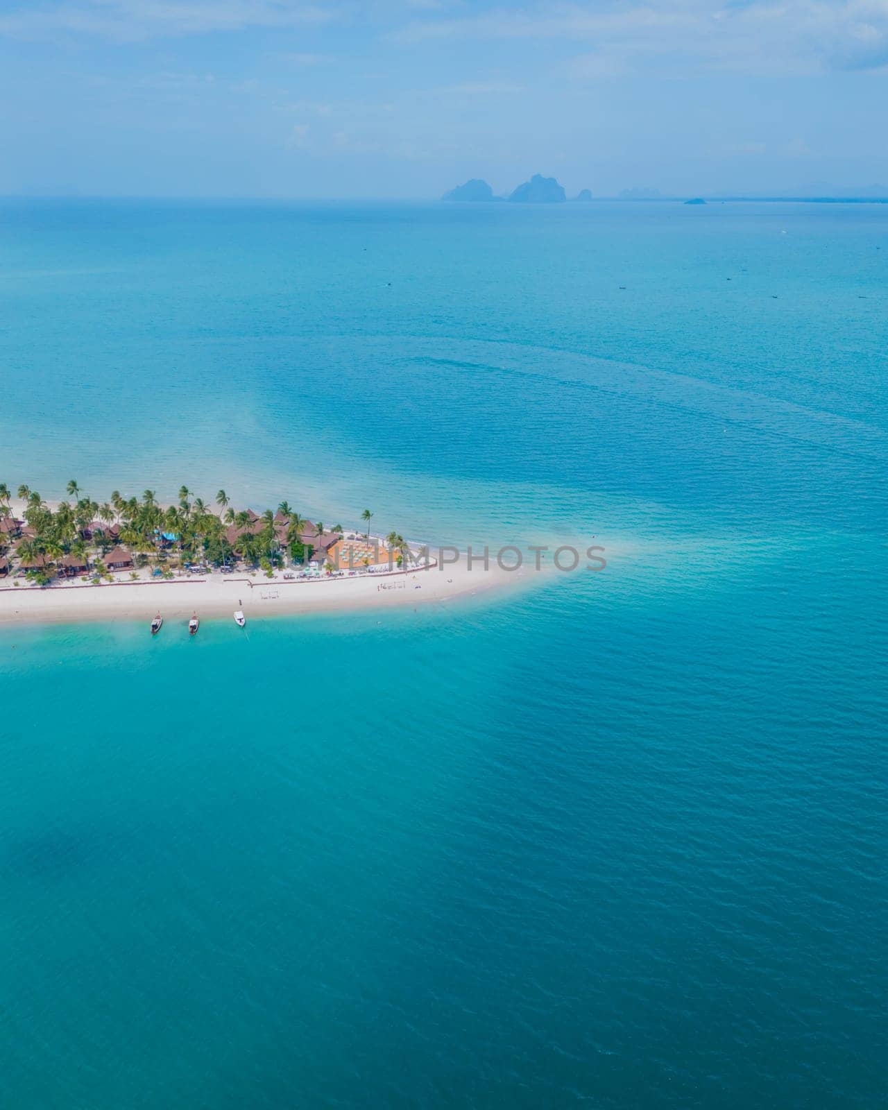 Koh Muk a tropical island with palm trees and soft white sand, and a turqouse colored ocean, drone top view at a sandbank in a blue turqouse colored ocean in Koh Mook Trang Thailand