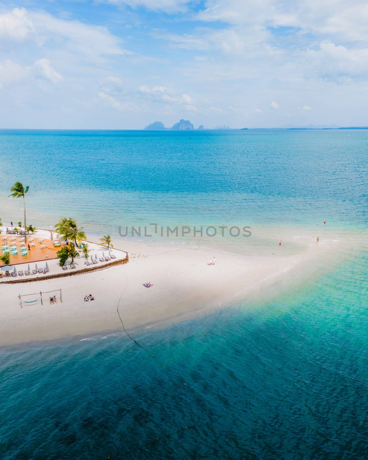 top drone view at Koh Muk a tropical island with palm trees and soft white sand, and a turqouse colored ocean in Koh Mook Trang Thailand
