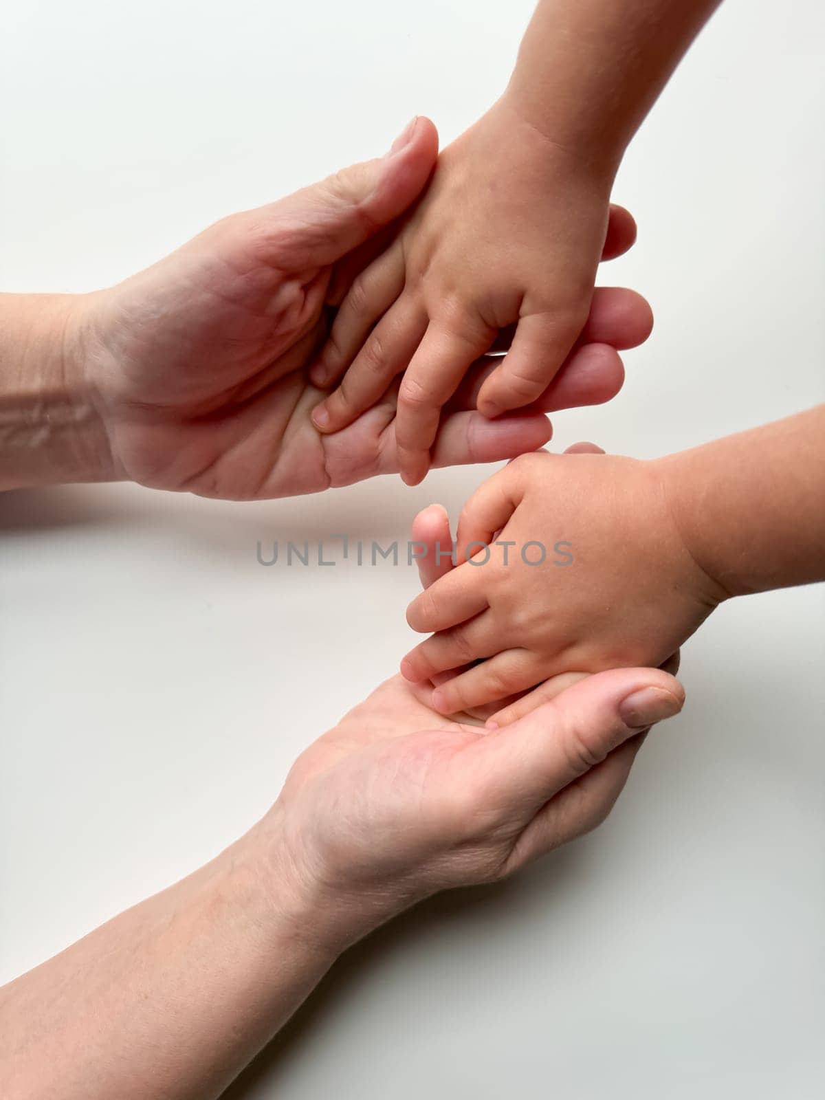 Woman and child, with their fingers intertwined, stand on a white surface. Their gestures express love and unity.