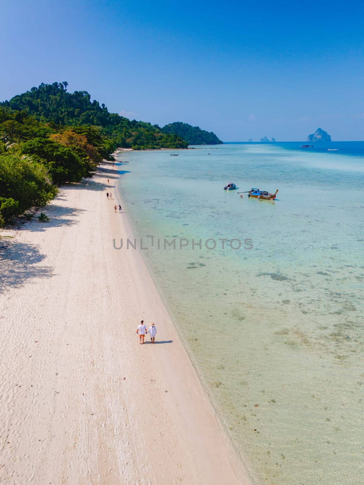 a couple on a boat trip to Koh Kradan a tropical island with palm trees soft white sand, and a turqouse colored ocean in Koh Kradan Trang Thailand, a popular island for snorkeling trips from koh lanta