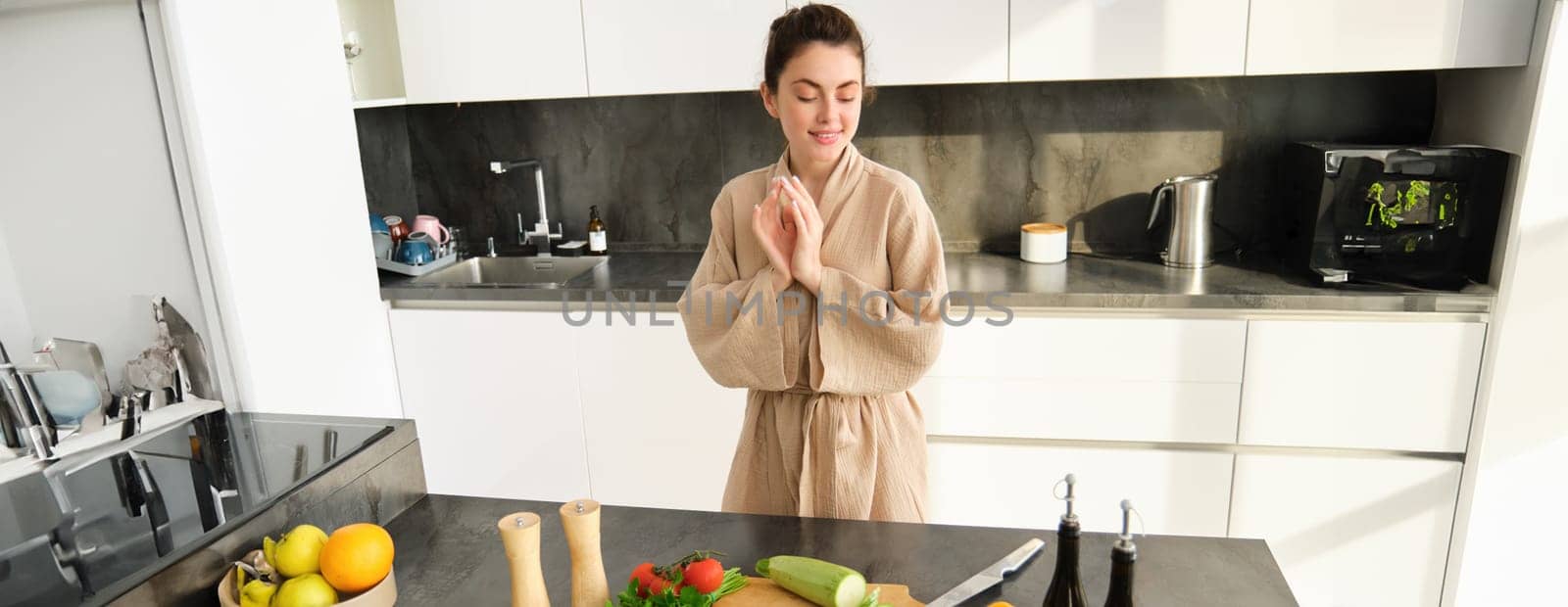 Portrait of woman in kitchen getting creative, thinking what to cook with vegetables, preparing healthy food, making dinner, looking at chopping board with zucchini and peppers by Benzoix