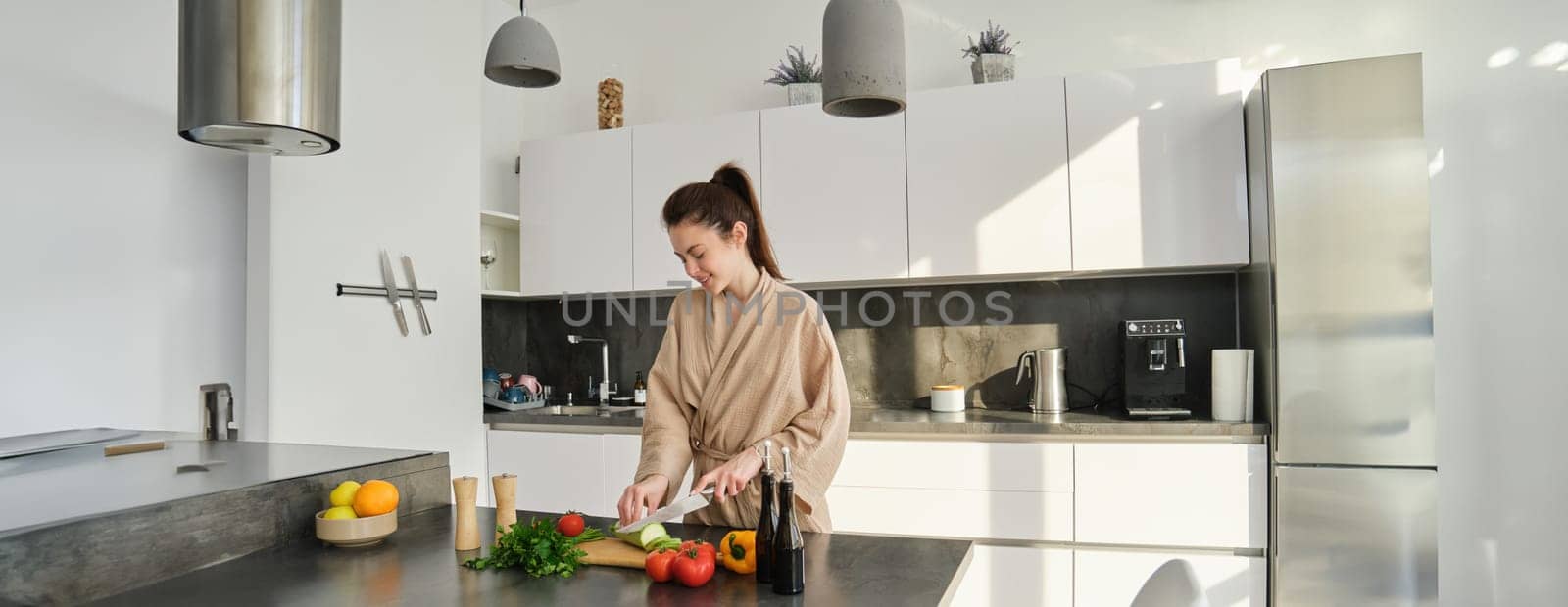 Portrait of beautiful brunette girl chopping vegetables for meal, making salad in the kitchen, eating healthy food, preparing dinner.