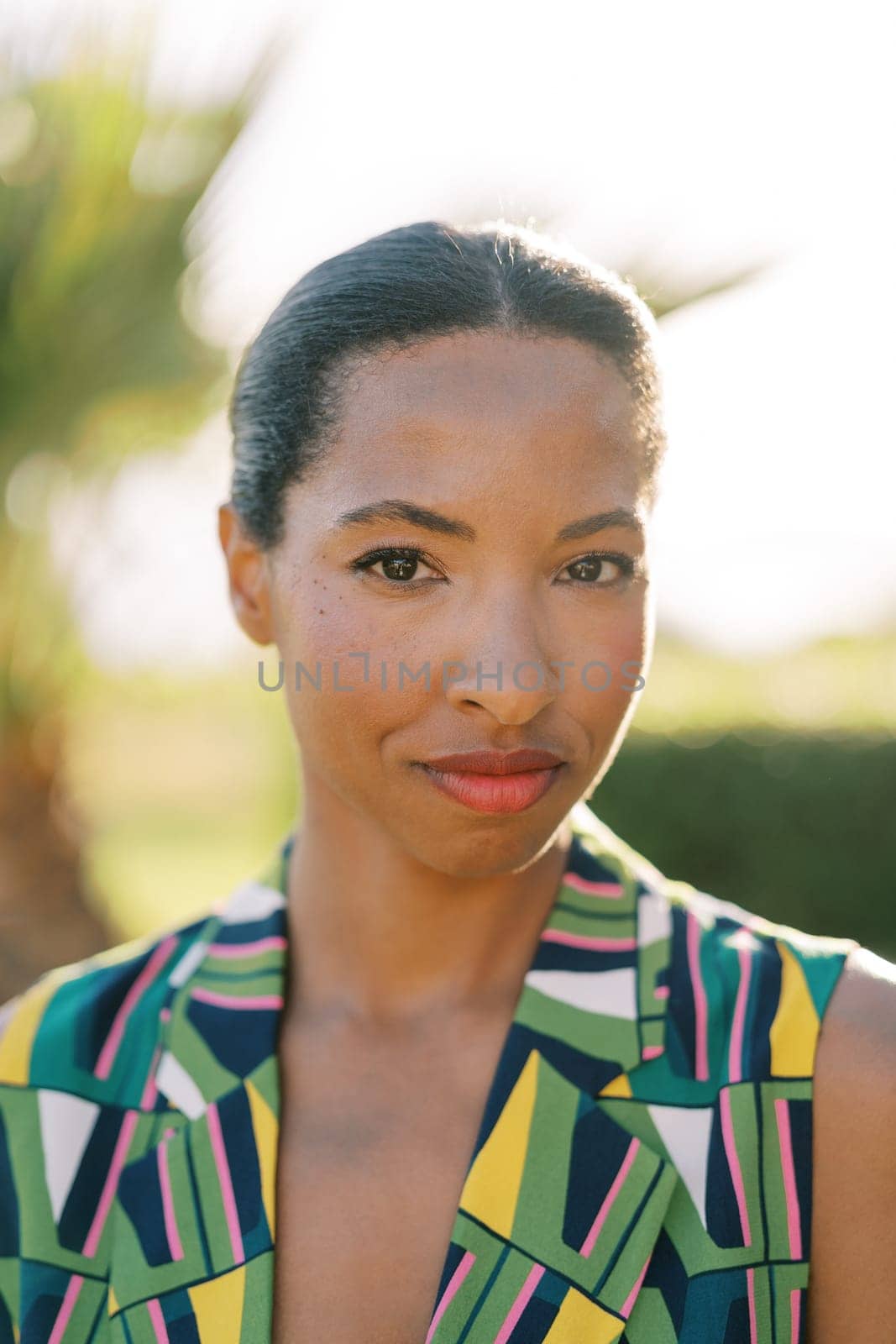 Young smiling woman is standing in a sunny garden. Portrait by Nadtochiy