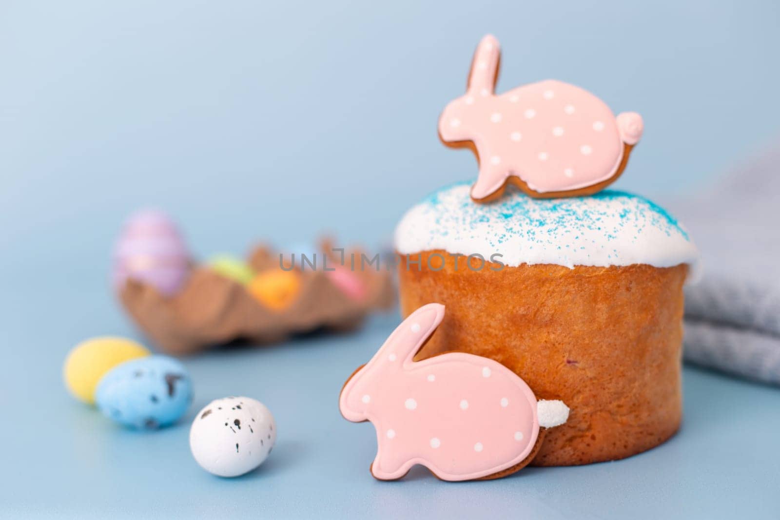 Pink gingerbread in the form of a rabbit on an Easter cake, small decorative multicolored quail eggs lie next to it.