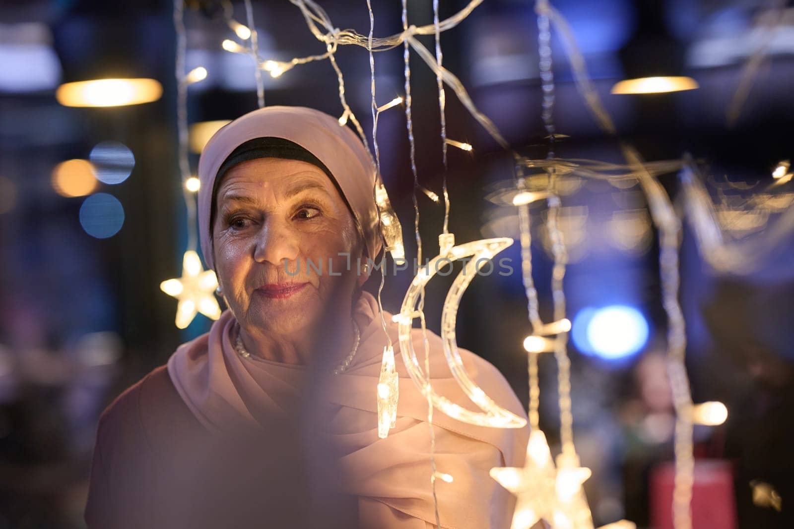 In a modern restaurant ambiance, a woman in a hijab captures a selfie beside glowing lights, showcasing contemporary style and cultural diversity in a trendy urban setting by dotshock