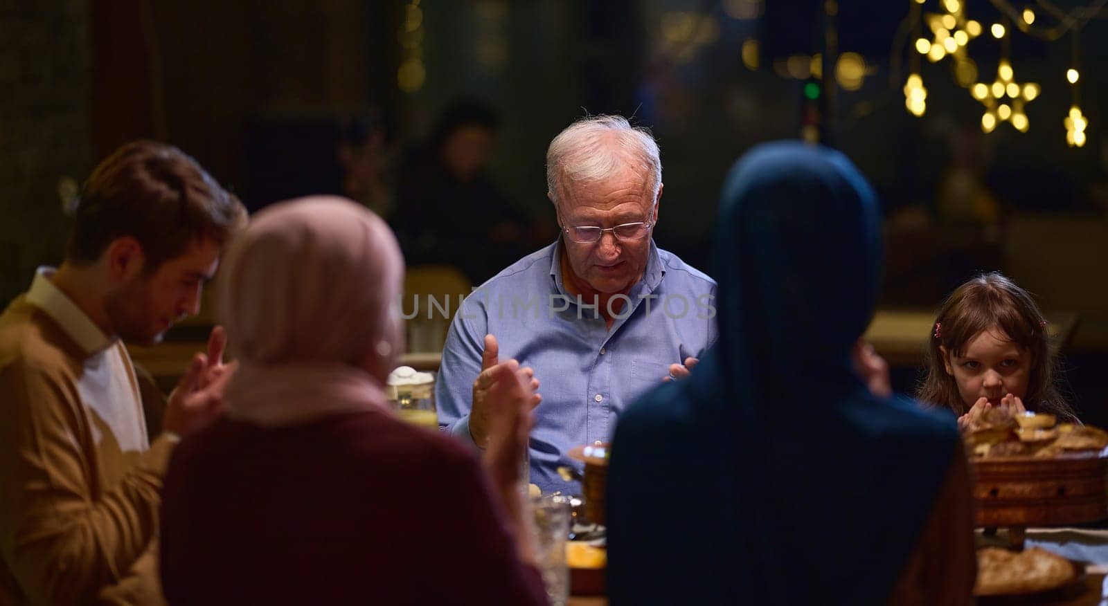 In a modern restaurant setting, a European Islamic family comes together for iftar during Ramadan, engaging in prayer before the meal, uniting tradition and contemporary practices in a celebration of faith and family by dotshock