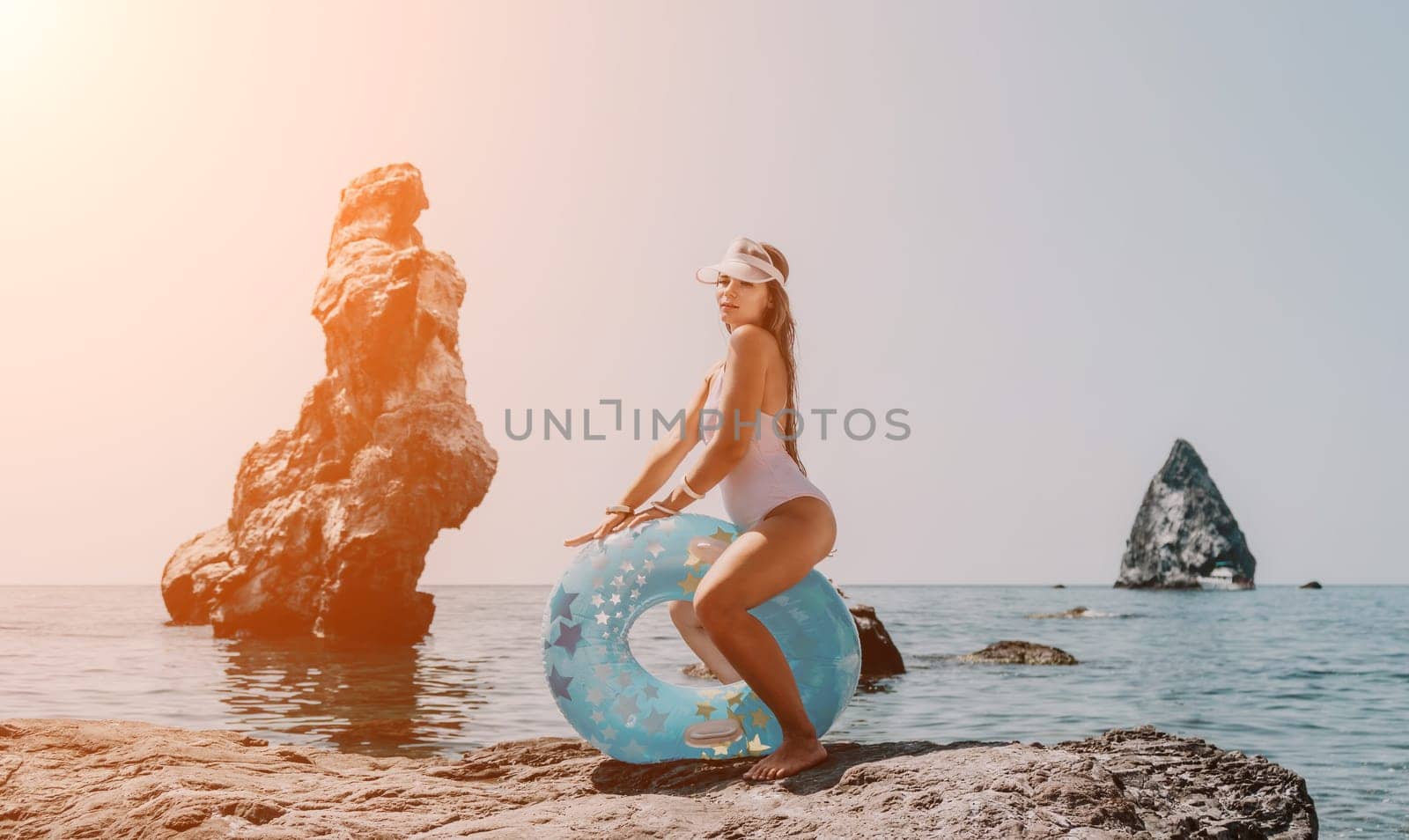 Woman summer sea. Happy woman swimming with inflatable donut on the beach in summer sunny day, surrounded by volcanic mountains. Summer vacation concept. by panophotograph