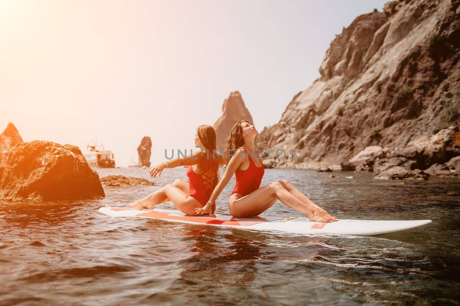 Woman sup yoga. Middle age sporty woman practising yoga pilates on paddle sup surfboard. Female stretching doing workout on sea water. Modern individual hipster outdoor summer sport activity