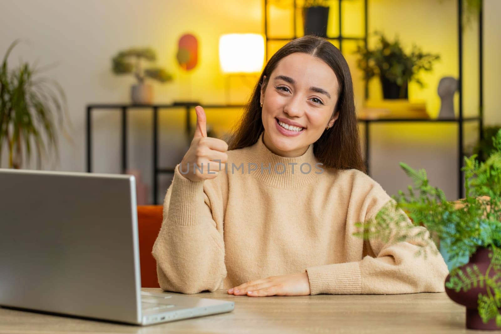 Like. Happy excited Caucasian woman looking approvingly at camera showing thumbs up like sign positive something good great news positive feedback. Girl sits at home office room at table. Copy-space