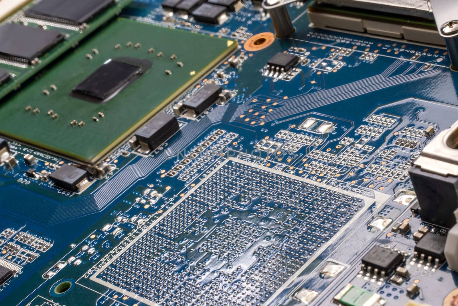 Concept laptop technology. A detailed shot of a computer motherboard, featuring a CPU, chipsets and circuit board showcasing the intricate engineering and composite materials used in its manufacturing. Bluegreen PCB. Selective focus