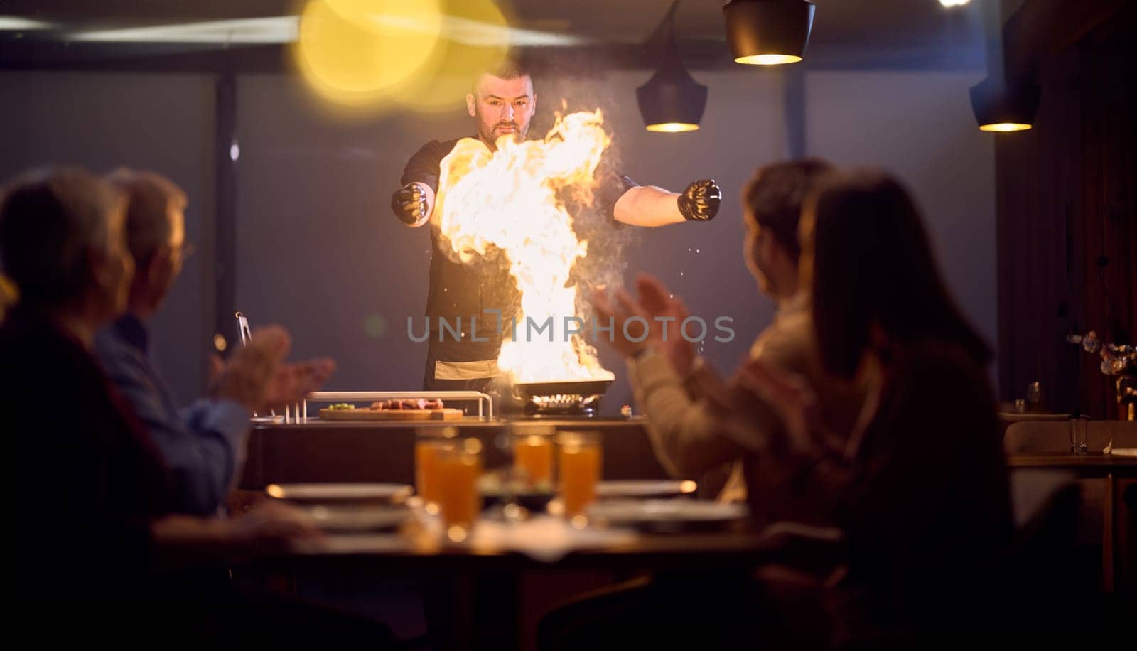 In a restaurant setting, a professional chef presents a sizzling steak cooked over an open flame, while an European Muslim family eagerly awaits their iftar meal during the holy month of Ramadan, blending culinary artistry with cultural tradition in a harmonious dining experience by dotshock