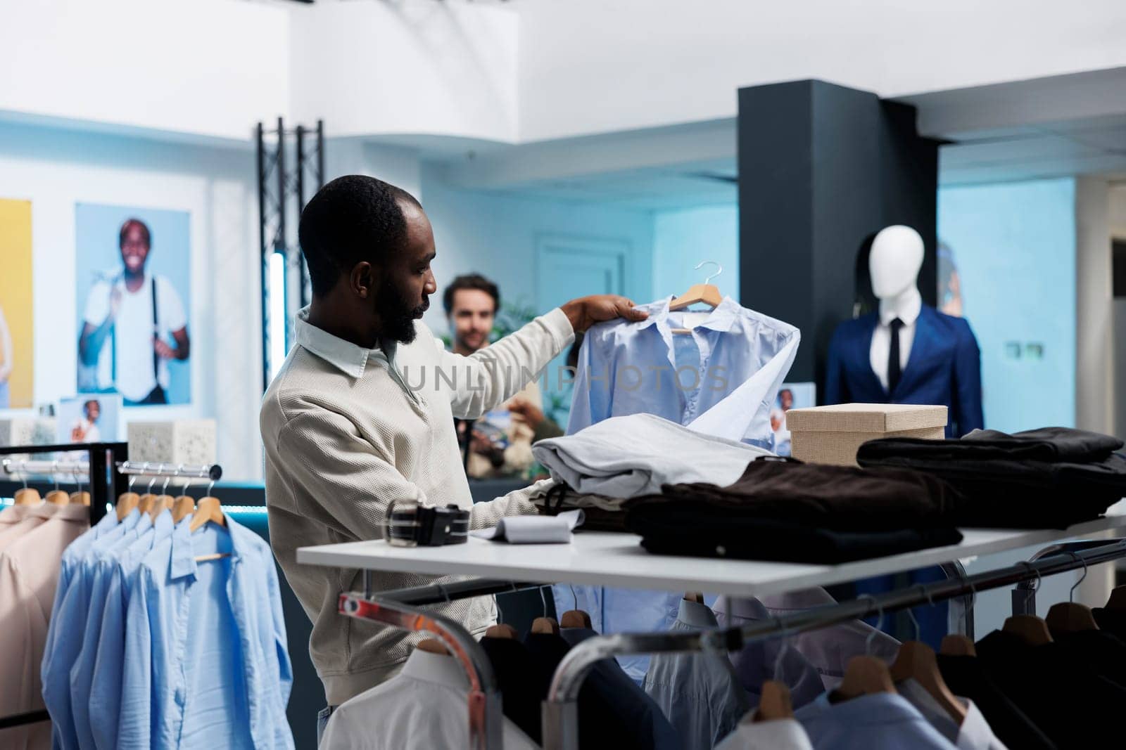 African american man checking shirt while exploring apparel rack in clothing store. Fashion boutique customer searching for formal garment while shopping in menswear section