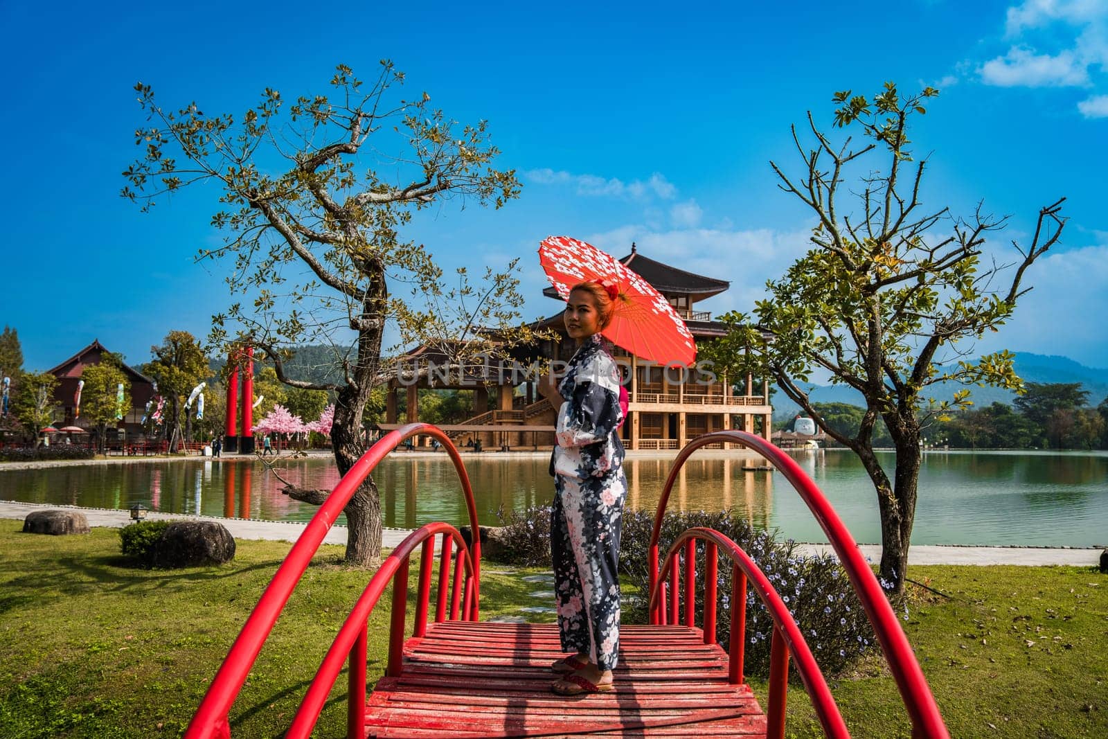 Asian girl in kimono and umbrella in Japanese theme park Hinoki Land in Chai Prakan District, Chiang Mai, Thailand by worldpitou