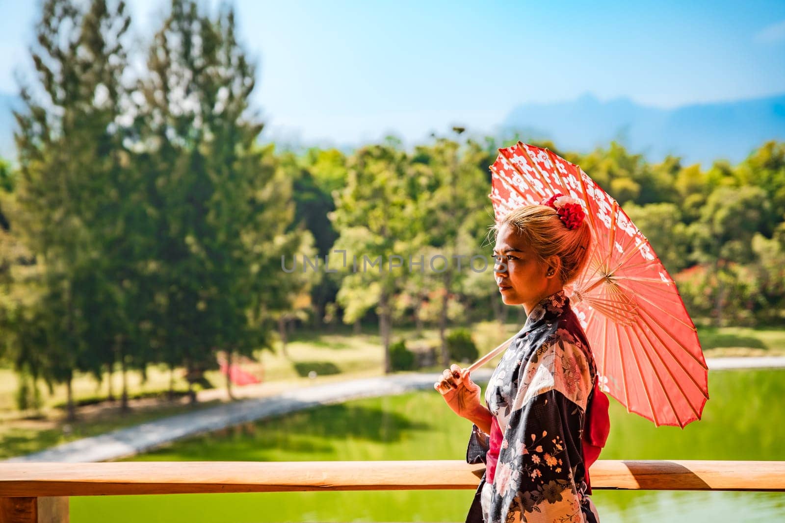 Asian girl in kimono and umbrella in Japanese theme park Hinoki Land in Chai Prakan District, Chiang Mai, Thailand by worldpitou