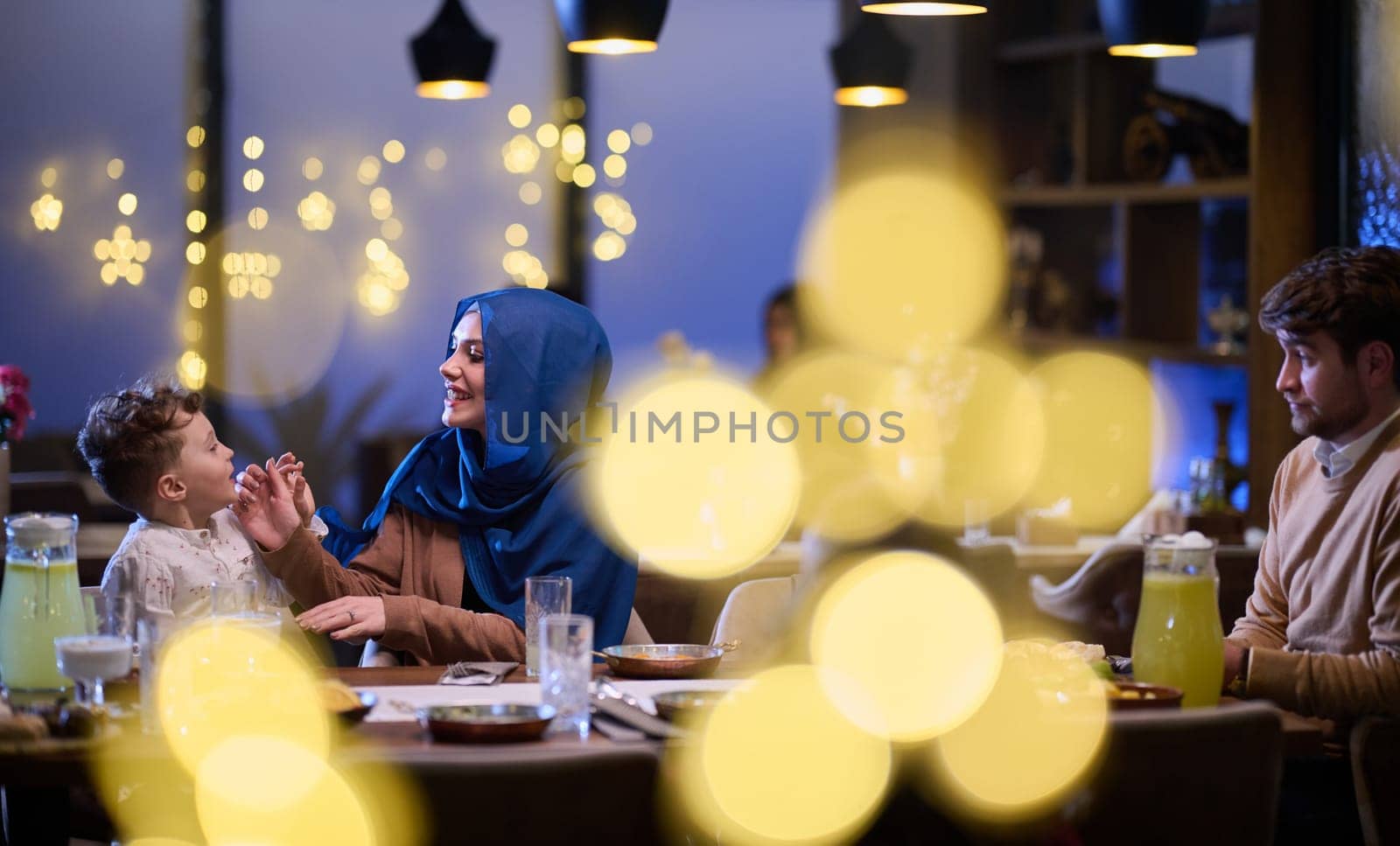 In a modern restaurant, an Islamic couple and their children joyfully await their iftar meal during the holy month of Ramadan, embodying familial harmony and cultural celebration amidst the contemporary dining ambiance.