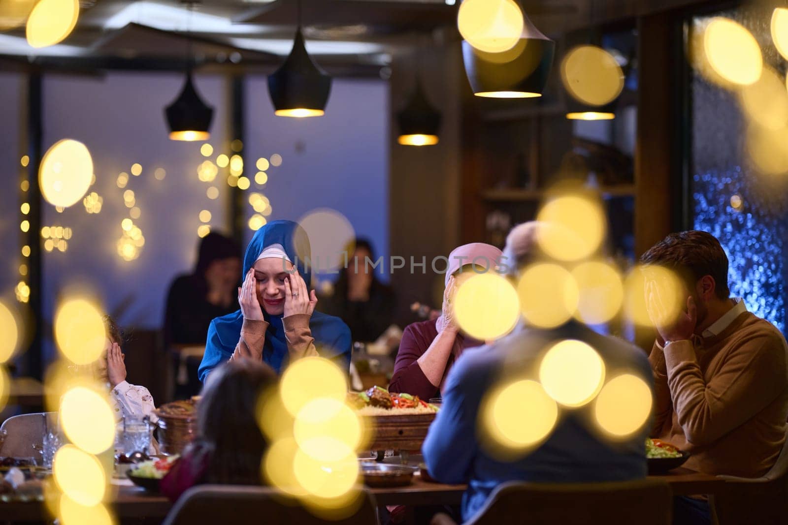 In a modern restaurant setting, a European Islamic family comes together for iftar during Ramadan, engaging in prayer before the meal, uniting tradition and contemporary practices in a celebration of faith and family.