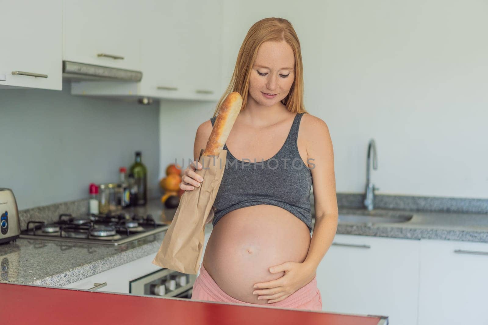 Pregnant woman eating bread in the kitchen. Exploring the impact of gluten during pregnancy: understanding the potential benefits and risks for maternal health and fetal development by galitskaya