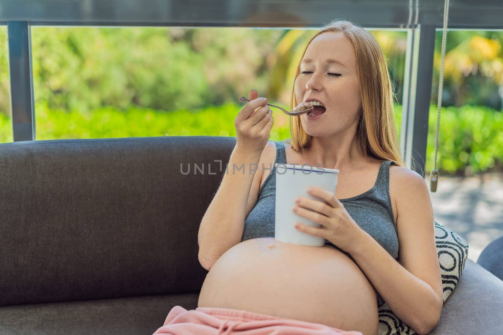 Happy pregnant young woman eating ice cream.