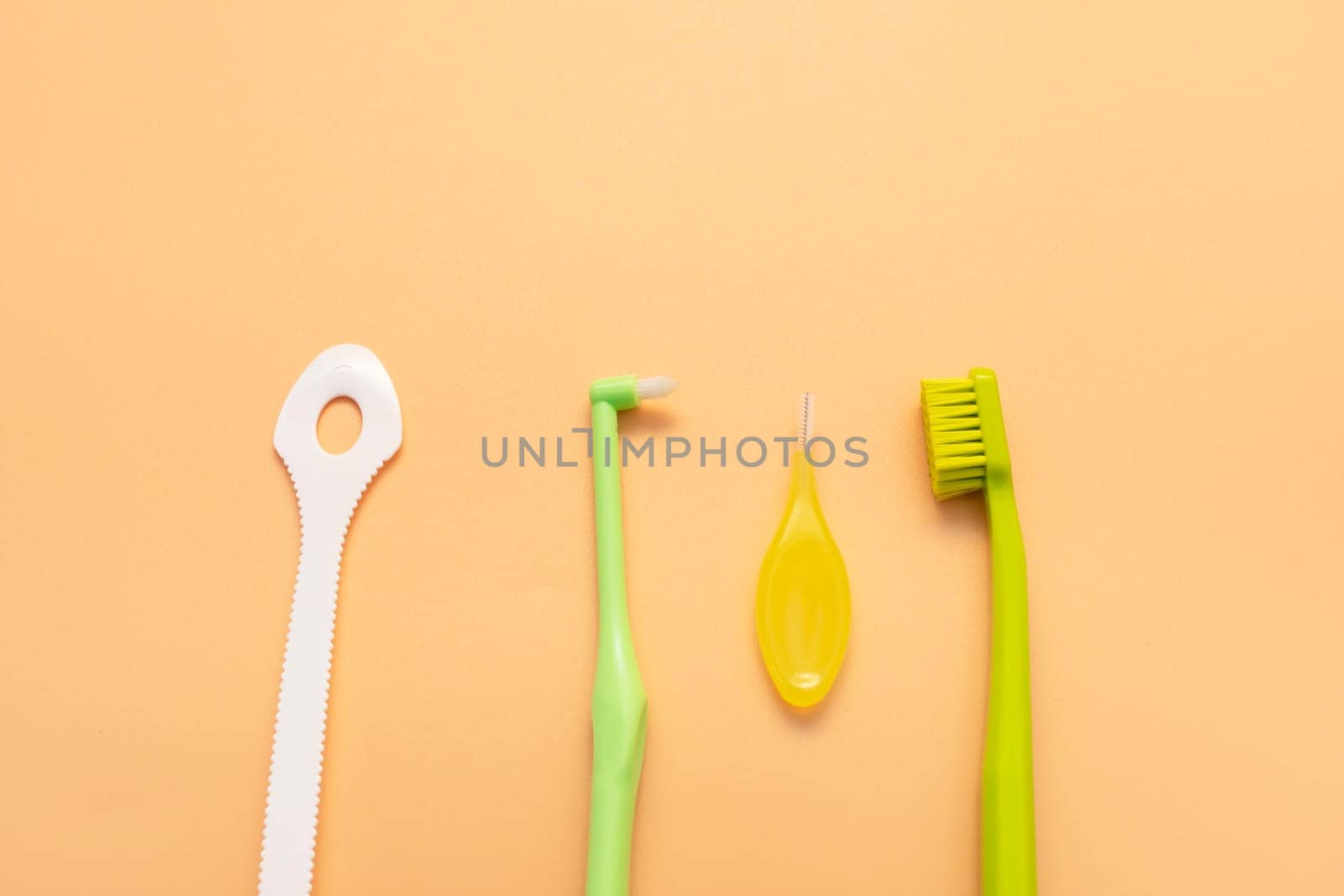 Personal Dental Oral Hygiene Set Kit. Tongue Scraper, Toothbrush, Interdental Toothbrush For Cleaning Between Teeth On Peach Yellow Background. Space For Text. Horizontal Plane by netatsi