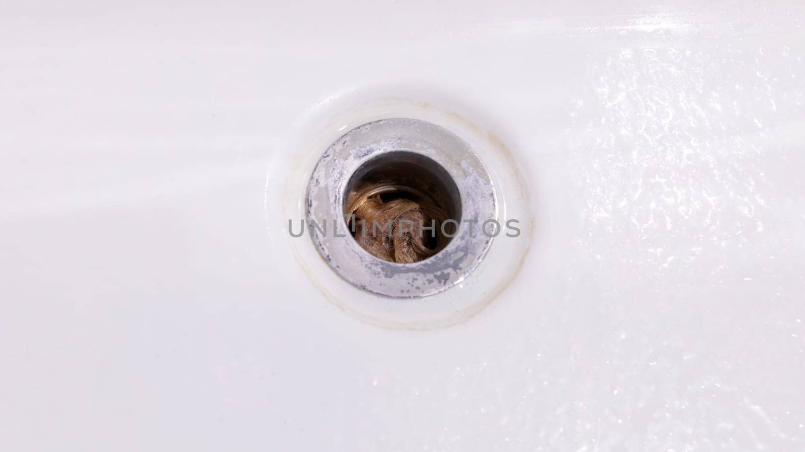 Closeup Clogs In Drain, Hair Loss, Hair Fall. Big Tuft Of Blond Hair In White Bathtub Hole Of Bathroom, Shower. Clogged Pipe. Plumbing Difficulties At Home. Thin Hair Problem. Horizontal Plane by netatsi