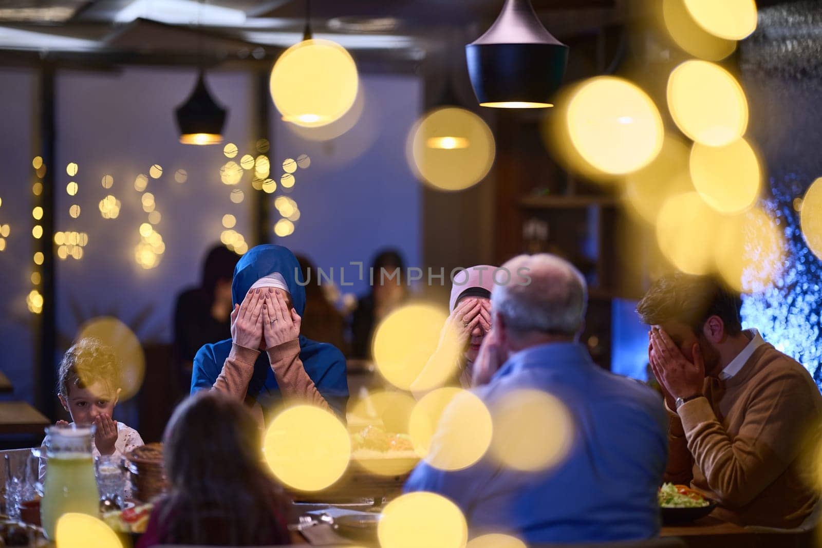 In a modern restaurant setting, a European Islamic family comes together for iftar during Ramadan, engaging in prayer before the meal, uniting tradition and contemporary practices in a celebration of faith and family.