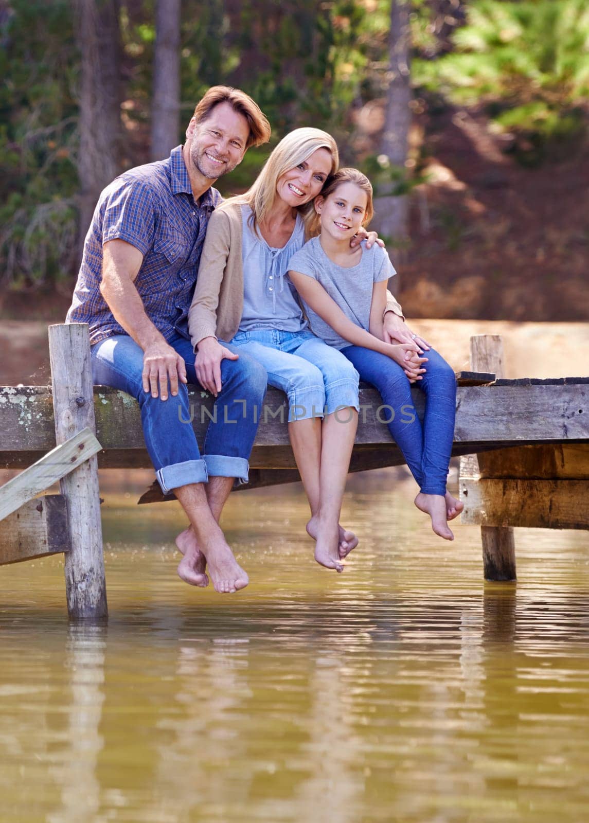 Portrait, lake and girl with family, smile and happiness with water or nature with vacation or getaway trip. Parents, hug or mother with father or child in a forest or holiday with boardwalk or relax.