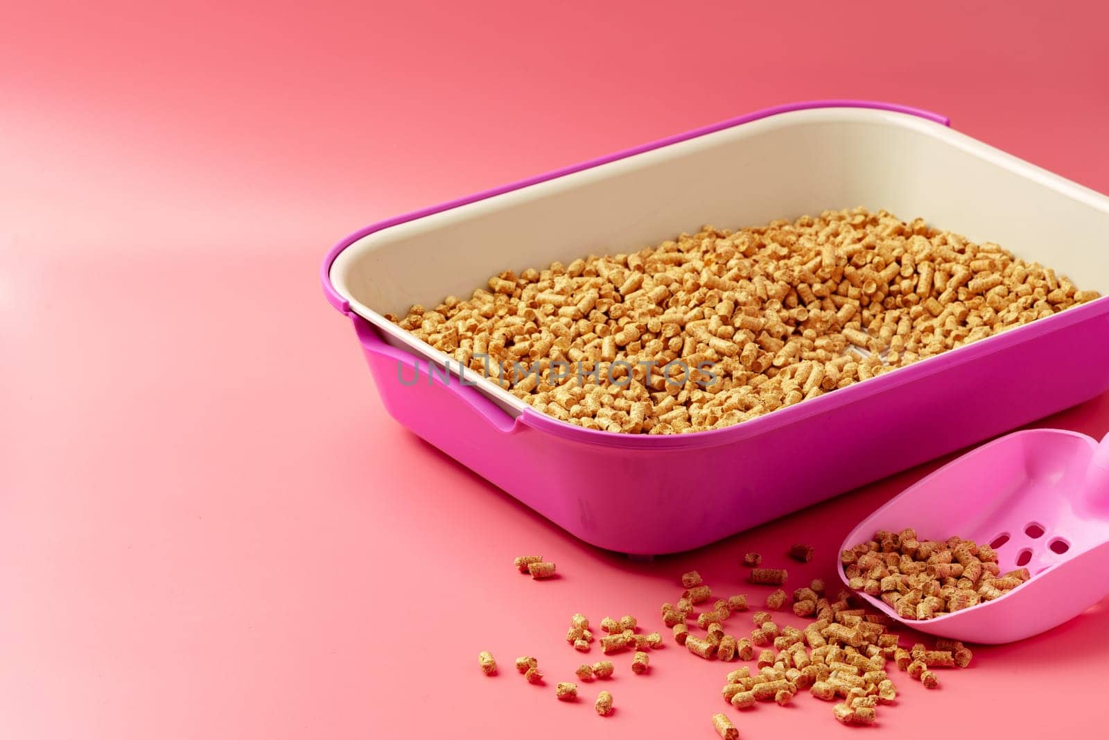 Pet litter box with bio filler on pink background close up