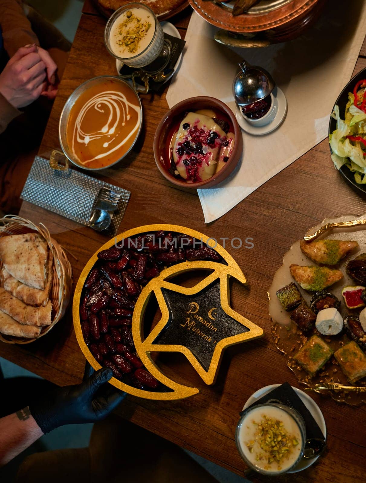 In this captivating aerial view, delicious food adorned with Ramadan decorations, including dates and meat, awaits the arrival of an European Islamic family, promising a festive and flavorful iftar celebration.