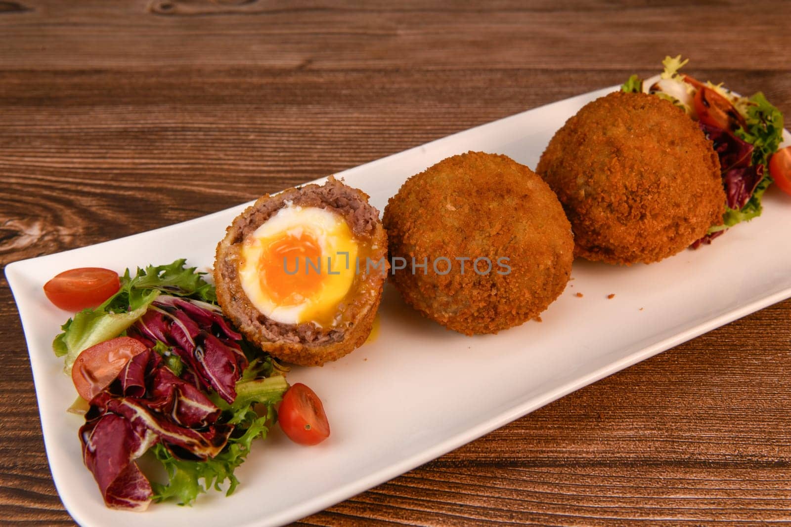 RECIPE FOR BREADED BEEF MEATBALLS STUFFED WITH A SOFT BOILED EGG. High quality photo