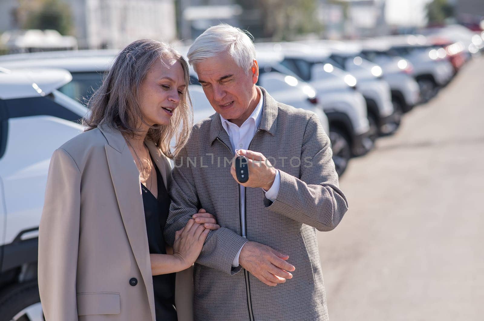 Mature Caucasian couple standing by a car outdoors. Elderly man holding car keys. by mrwed54
