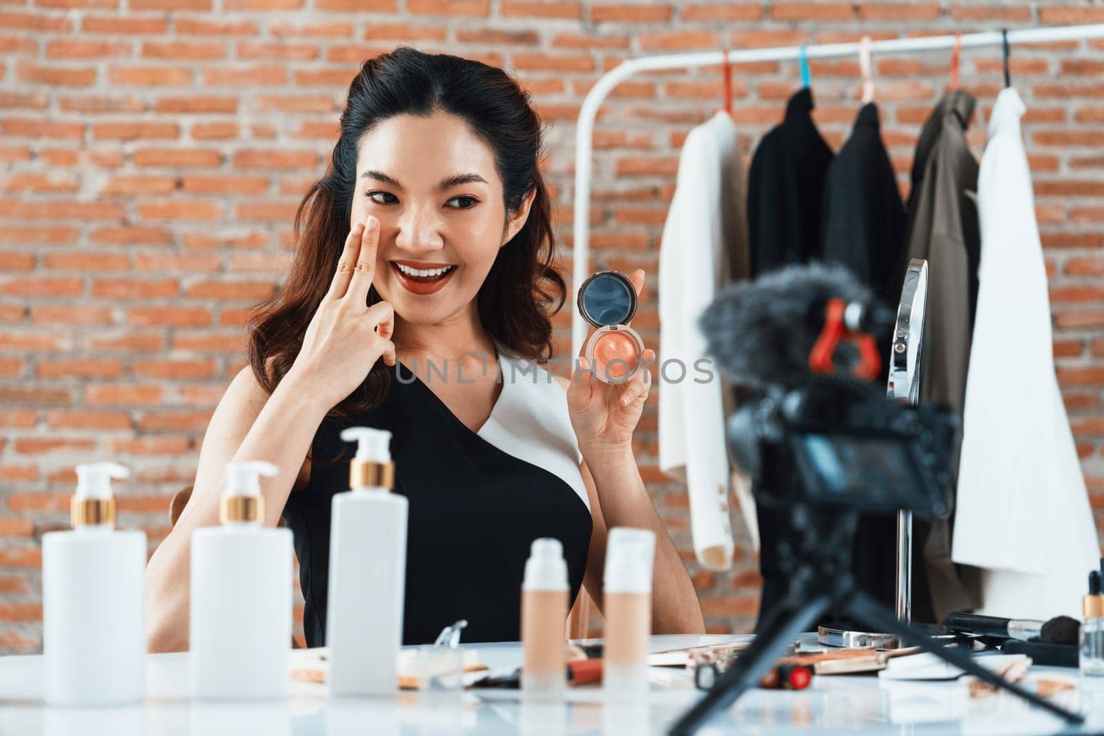 Asian Woman influencer shoot live streaming vlog video review makeup uttermost social media or blog. Happy young girl with cosmetics studio lighting for marketing recording session broadcasting online