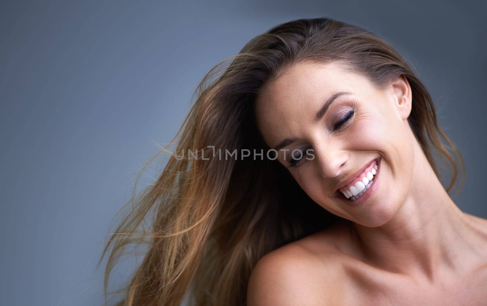 Hair, beauty and happy woman in studio with cosmetics, shampoo or treatment results on grey background. Haircare, smile and model with growth, shine or texture satisfaction or clean scalp confidence.