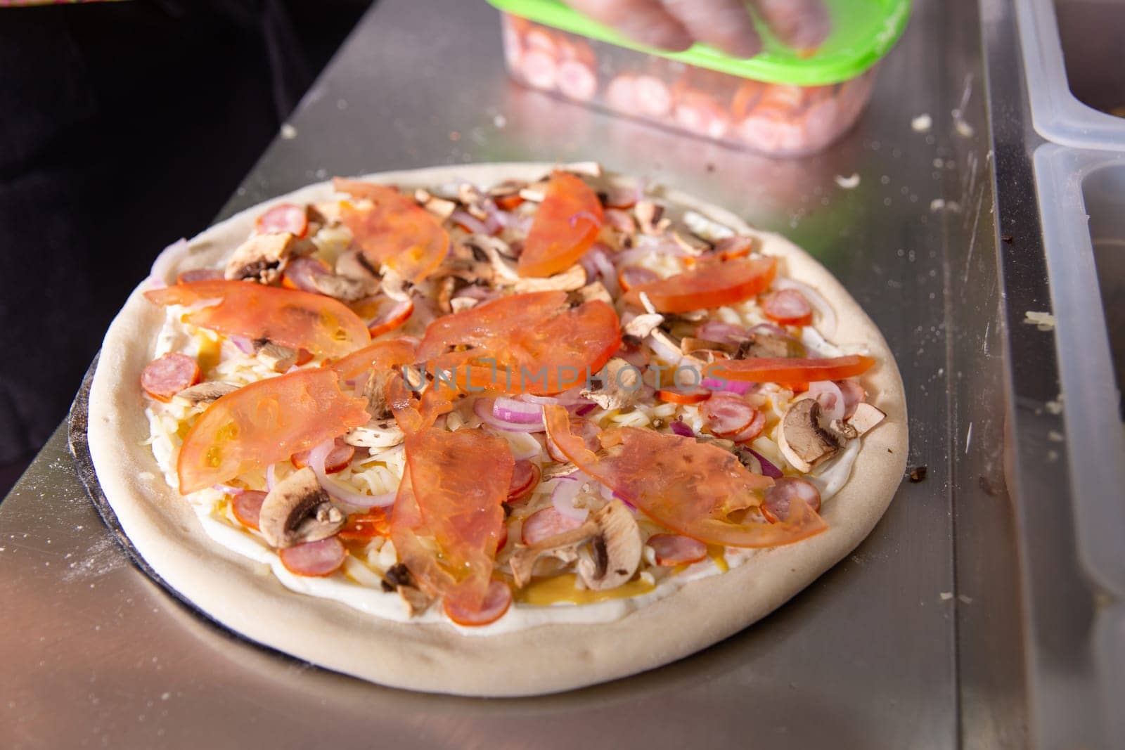 The chef prepares a classic Italian pizza with sausages, mushrooms and tomatoes. by BY-_-BY