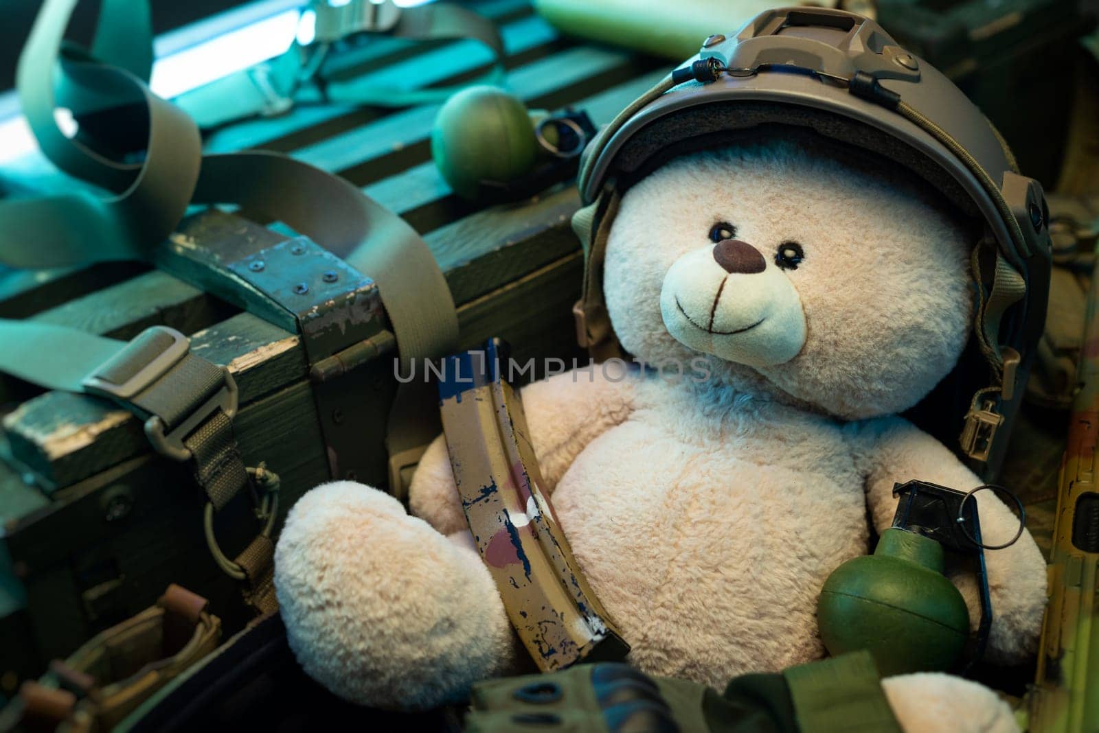 teddy bear in a military helmet among a pile of military ammunition, a rifle, grenades, a bulletproof vest, a helmet and other tactical airsoft items