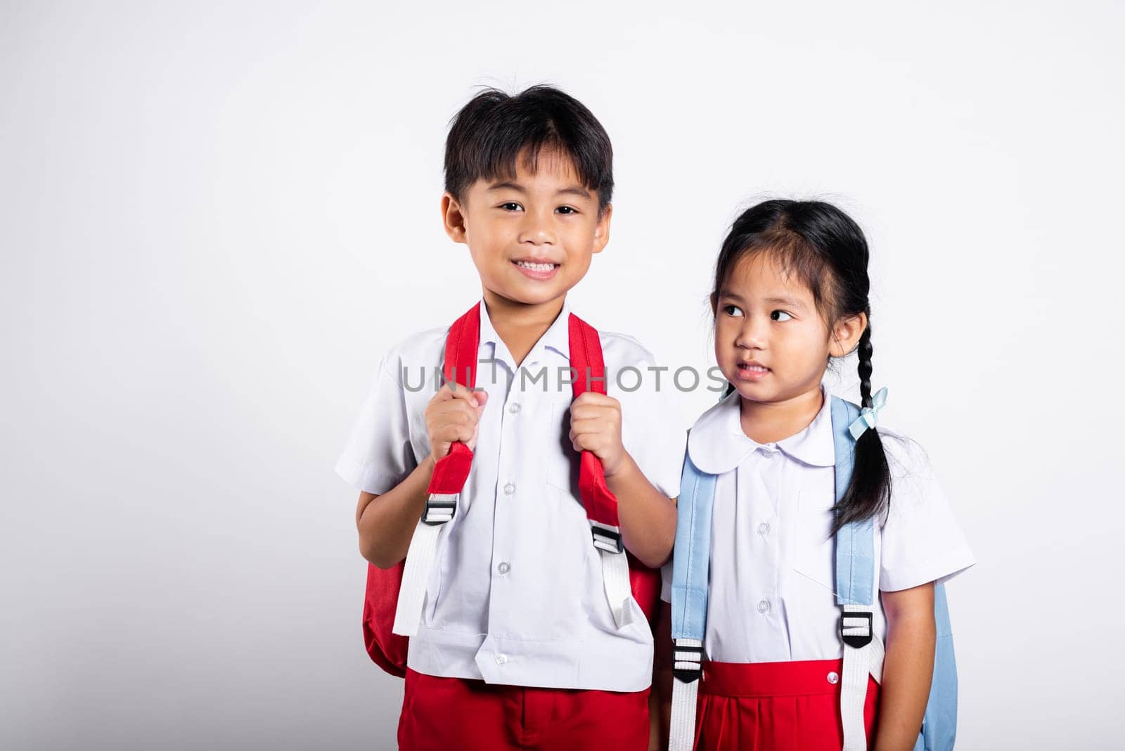 Two Asian student kid girl boy schoolchildren brother sister smile happy wear student thai uniform red pants skirt in studio shot isolated on white background, Portrait little children girl preschool