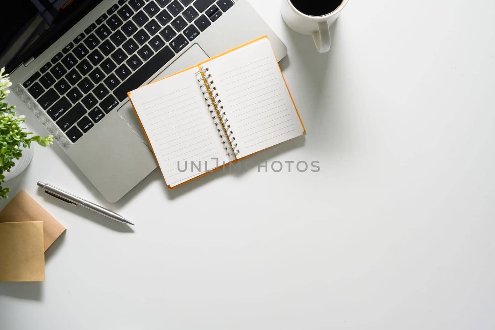 White office desk with laptop, notepad and coffee cup. Flat lay, top view with copy space.