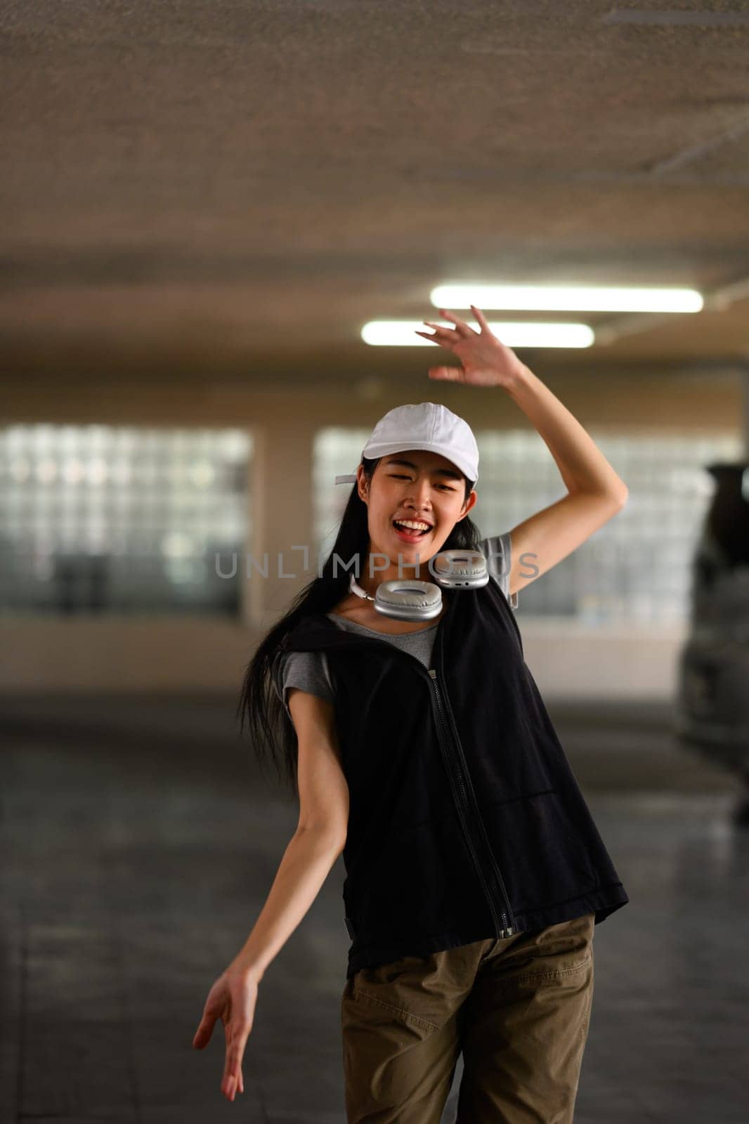 Smiling young woman breakdancing in underground parking lot .Concept of action, sport, youth lifestyle.