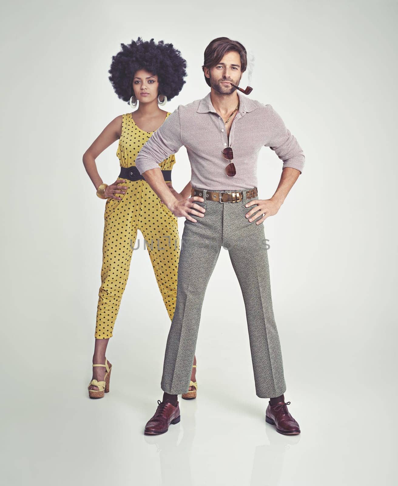 Couple, portrait and fashion in confidence with pipe for smoking, style or outfit on a gray studio background. Interracial man, woman or smoker in stylish retro and vintage pants, shirt or jumpsuit.