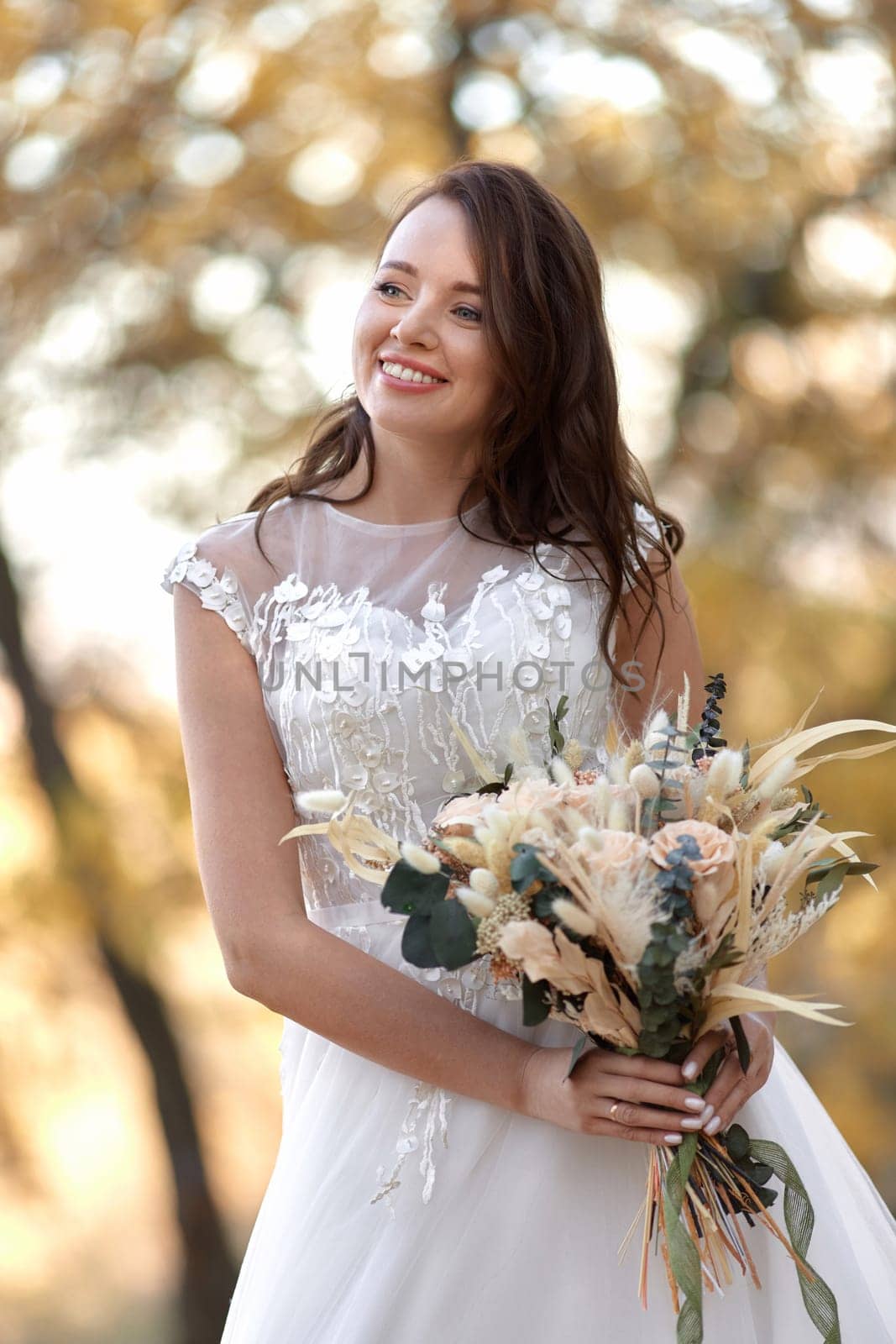 beautiful happy bride holding wedding autumn bouquet in nature