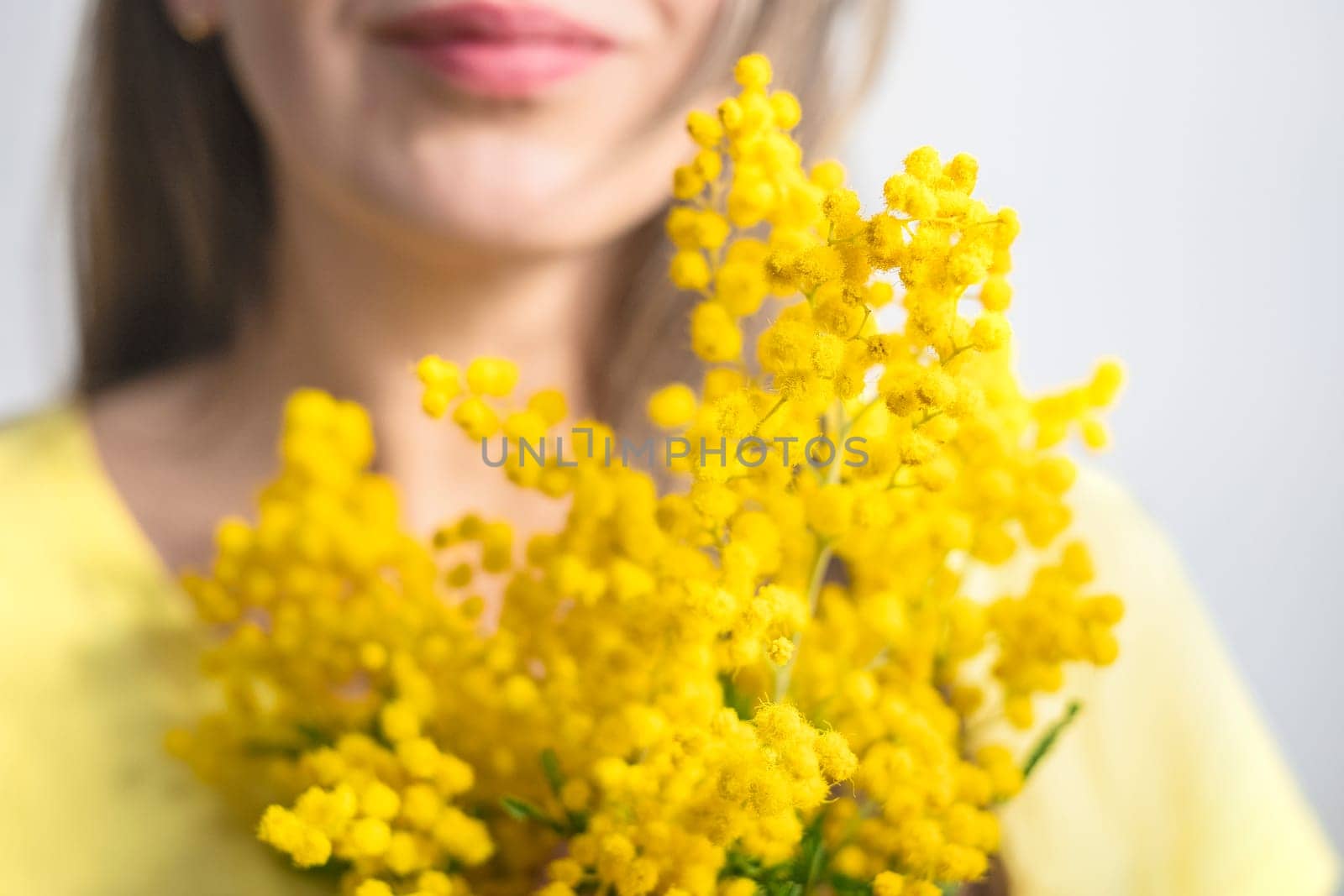 Beautiful young woman with mimosa flowers on white background. Close up