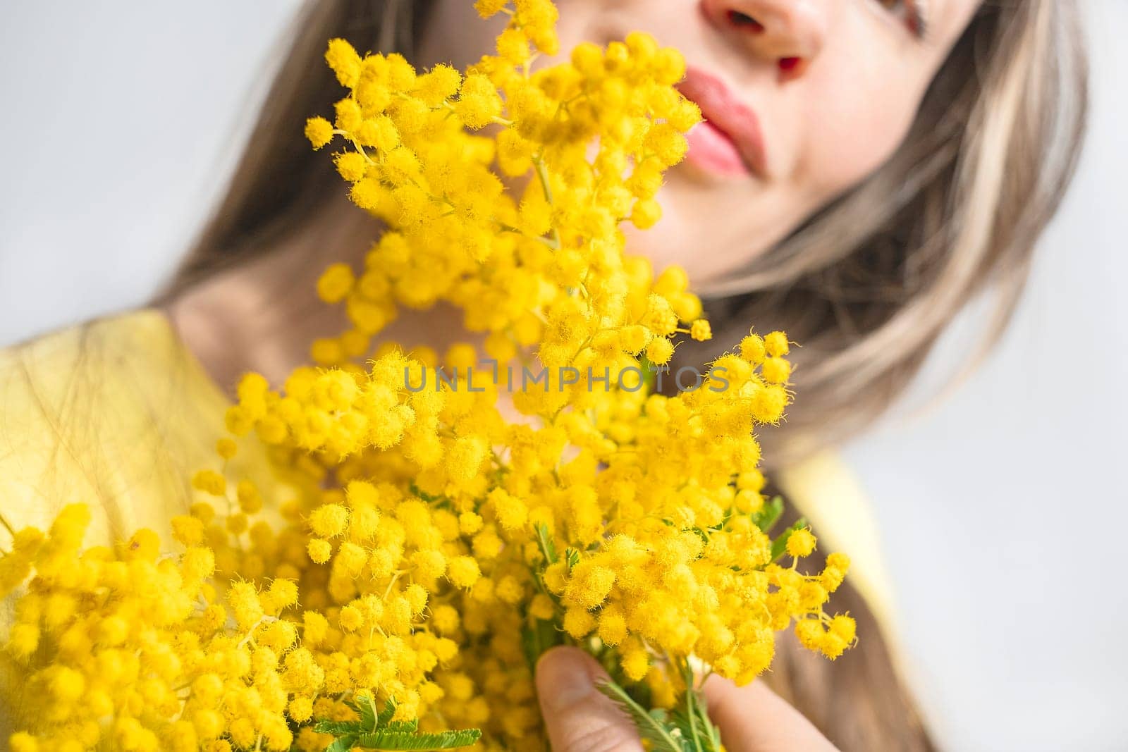 Beautiful young woman with mimosa flowers on white background. Close up
