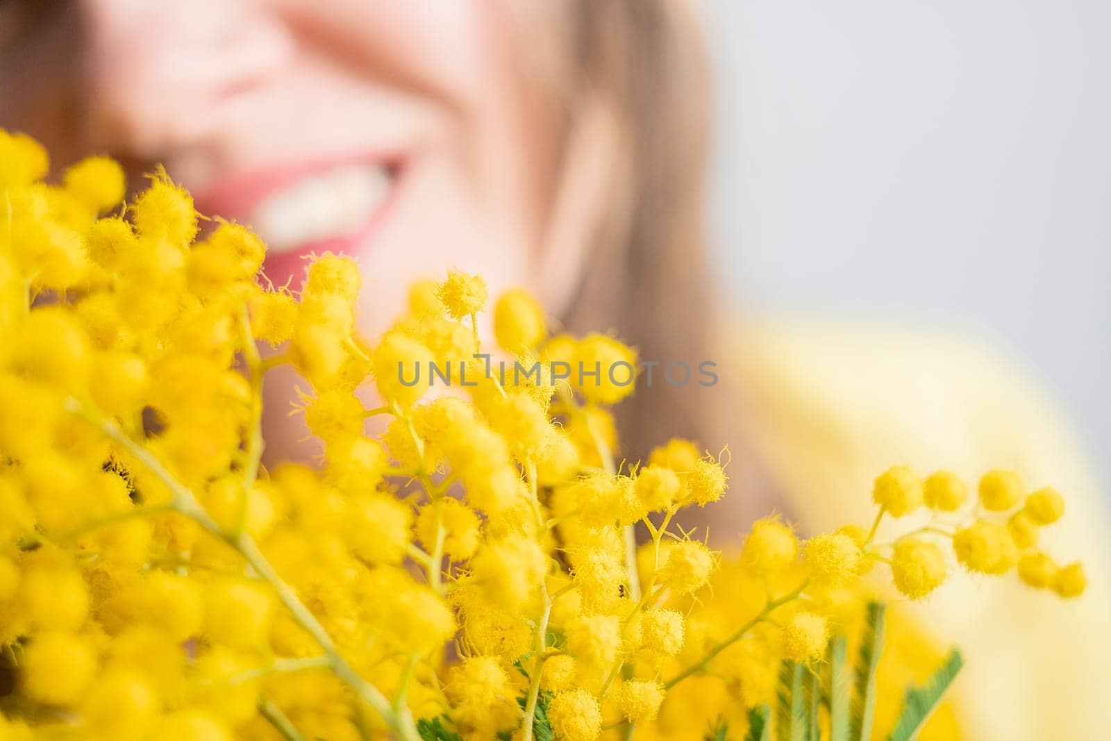 Beautiful young woman with mimosa flowers on white background. Close up